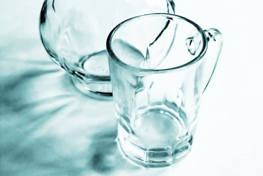 Verre transparent à facettes et carafe en verre dans une lumière bleutée.
